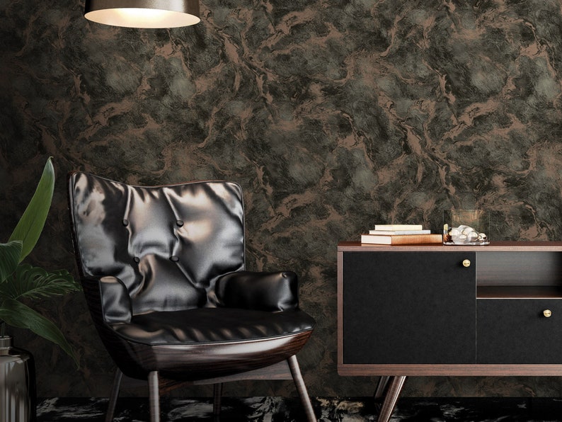 K&ouml;nnte beinhalten: Ein schwarzer Ledersessel mit einer gesteppten R&uuml;ckenlehne und einem dunklen Holzrahmen steht vor einer Wand mit einer braunen und gr&uuml;nen Marmortapete. Rechts vom Sessel steht ein schwarzer Schrank mit einer Holzplatte und goldenen Kn&ouml;pfen.
