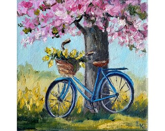 May include: A blue bicycle with a basket full of yellow flowers is parked under a pink flowering tree. The bicycle has a brown wicker basket and a brown seat. The tree is in full bloom and the flowers are a vibrant pink.