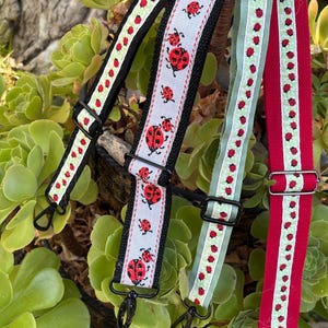May include: Three adjustable bag straps featuring ladybug patterns. One strap has a white background with red ladybugs and black edges. Another is a light green strap with tiny red ladybugs. The third is a red strap with a light green ladybug trim.