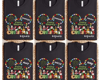 May include: Black t-shirts with a Christmas theme. Each shirt features a heart-shaped design with the words "Very Merry Christmas Squad" and a family member's title, such as "Grandpa" or "Cousin". The design includes colorful fireworks and cartoon characters.