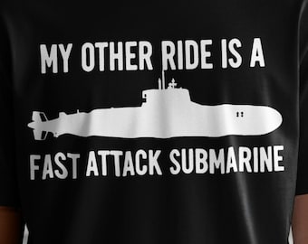 May include: Black t-shirt featuring the white text "MY OTHER RIDE IS A FAST ATTACK SUBMARINE" and a submarine graphic. The shirt is worn by a person. The design is simple and bold.