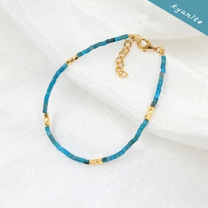 May include: A delicate blue kyanite gemstone bracelet with gold accents. The bracelet features a lobster clasp closure.