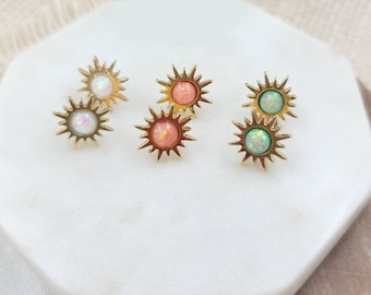 May include: Six gold sun-shaped earrings with opal-like stones in white, pink, and green.