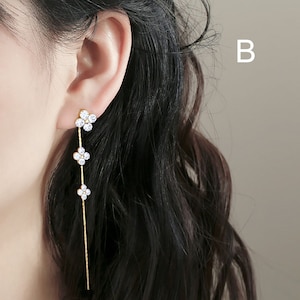 May include: Gold dangle earrings with three flower-shaped charms set with clear cubic zirconia stones.