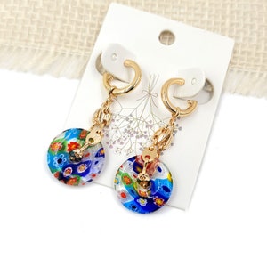 May include: A pair of gold hoop earrings with a colorful glass charm. The charms are round and feature a variety of colors, including blue, green, red, and white.