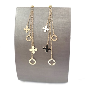 May include: Gold tone dangle earrings with multiple chains and four charms. Each earring has three circular charms and two flower charms. The flower charms are open and have a cutout design.