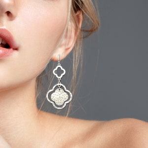 May include: Silver dangle earrings with a hammered, textured, clover-shaped design.