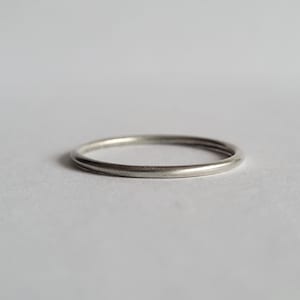 May include: A simple silver band ring.