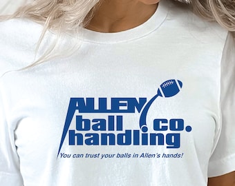 Puede incluir: Camiseta blanca con el texto azul "ALLEN ball handling co." y un gráfico de fútbol americano azul. La camiseta también incluye la frase "You can trust your balls in Allen's hands!"