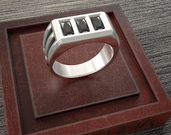 May include: A silver ring with three black rectangular stones set in a thick band.