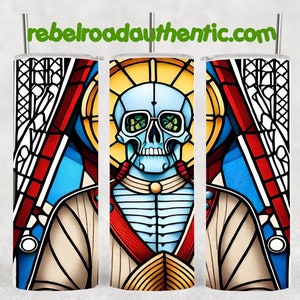 May include: A stainless steel tumbler with a stained glass design featuring a blue skull with green eyes and a red and gold halo. The design is reminiscent of a religious icon.