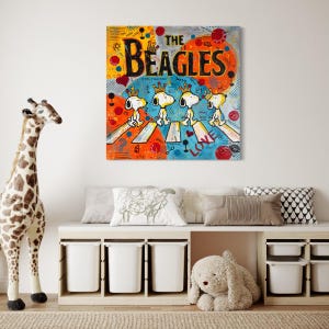 May include: A colorful pop art style canvas print featuring Snoopy and his friends crossing a street, a parody of the Beatles' Abbey Road album cover. The artwork is titled "The Beagles" and is displayed above a white storage bench.