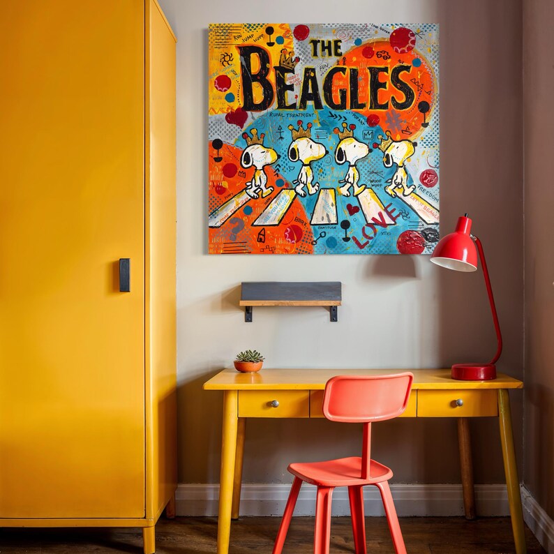 May include: A colorful pop art style canvas print featuring Snoopy and Woodstock characters crossing a street, with the words "THE BEAGLES" in large black letters. The artwork hangs above a yellow desk and red chair.