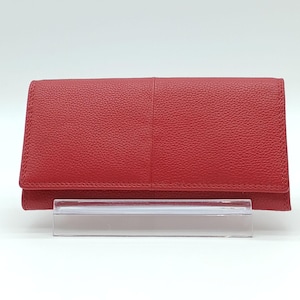 May include: A red leather wallet with a textured surface. The wallet is rectangular with a fold-over flap and is displayed on a clear acrylic stand. The wallet appears to be new.
