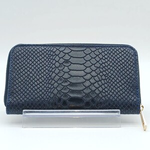 May include: A navy blue wallet with a snakeskin pattern. The rectangular wallet has a zipper closure and a gold-colored zipper pull. The wallet is displayed on a clear stand against a white background.