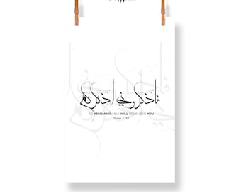 May include: A white poster with black Arabic calligraphy and English text. The calligraphy reads "So remember me: I will remember you" from Quran 2:152. The poster is held by two wooden clips.