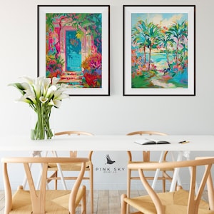 May include: Two framed paintings on a white wall. The painting on the left shows a blue door with a pink and green floral design. The painting on the right shows a beach scene with palm trees and a turquoise ocean.