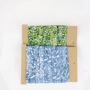 Peut inclure: Deux rouleaux de bandes de tissu, l'un vert à pois blancs et l'autre bleu à pois blancs, sont enroulés autour de noyaux en carton.