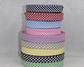 May include: A stack of eight gingham ribbon rolls in various colors, including black, red, blue, pink, purple, beige, yellow, and green.