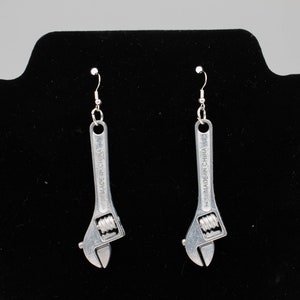 May include: A pair of silver wrench earrings with a hook closure. The wrenches are marked "Made in China."
