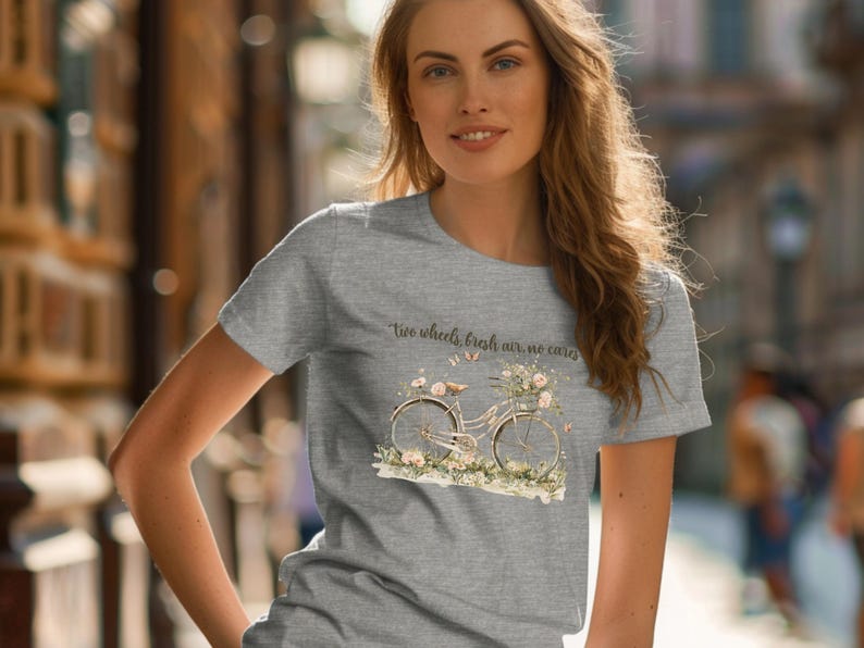 May include: A heather grey t-shirt with a floral design featuring a bicycle with the text "Two wheels, fresh air, no cares".