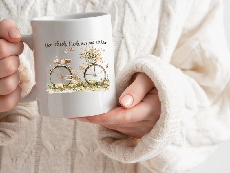 May include: White ceramic mug with a floral design and a bicycle with the text "two wheels, fresh air, no cares".