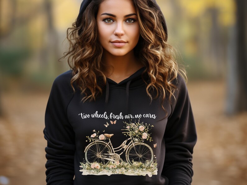 May include: Black hoodie with a white graphic of a bicycle with flowers and butterflies. The text "two wheels, fresh air, no cares" is printed on the hoodie.