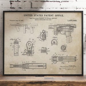 May include: Framed vintage patent print of a firearm, featuring detailed technical drawings and diagrams. The print is labeled "United States Patent Office" and includes the patent number 1,425,808. The artwork is in black and white, set against a beige background.