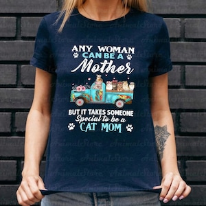 Puede incluir: Camiseta azul marino con el texto "ANY WOMAN CAN BE A Mother" y "BUT IT TAKES SOMEONE Special to be a CAT MOM". El dise&ntilde;o presenta un cami&oacute;n azul con gatos y flores.