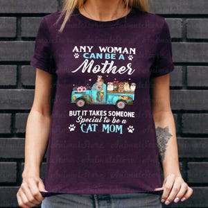 Puede incluir: Camiseta morada con el texto "ANY WOMAN CAN BE A Mother BUT IT TAKES SOMEONE Special to be a CAT MOM". El dise&ntilde;o presenta un cami&oacute;n azul con gatos y flores.