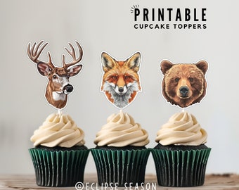 May include: Printable cupcake toppers featuring a deer, fox, and bear. The toppers are printed on white cardstock and have a glossy finish. The cupcakes are frosted with vanilla buttercream and have green cupcake liners.
