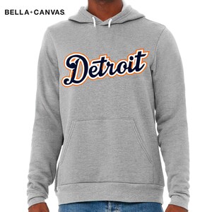 May include: A gray hooded sweatshirt with the word "Detroit" in a navy blue and orange script font.