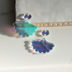 Puede incluir: Abalorios en forma de abanico de acrílico iridiscente y cuentas redondas. Los abalorios tienen un borde festoneado y un agujero para ensartar. Las cuentas también tienen agujeros. Los colores cambian de azul a verde a morado. Ideal para hacer joyas.