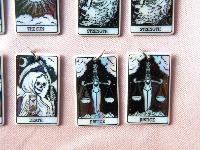 Puede incluir: Conjunto de diez cartas de tarot con acabados iridiscentes. Las cartas presentan im&aacute;genes del Sol, la Fuerza, la Muerte, la Justicia y una segunda carta de Justicia. Las cartas son blancas con detalles negros y plateados.