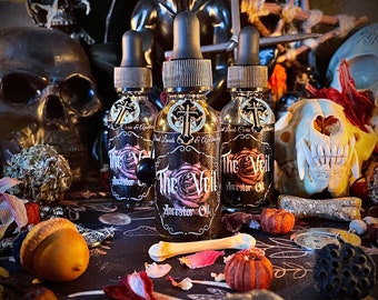 May include: Three glass bottles of "The Veil Ancestor Oil" with black droppers and labels featuring a rose design and cross. The bottles are surrounded by skulls, bones, and small pumpkins, creating a mystical and gothic aesthetic.