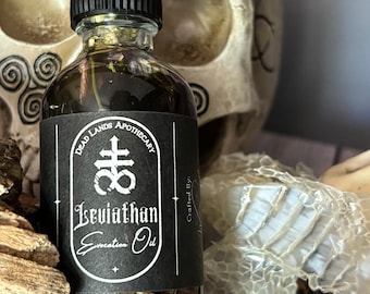 May include: A black glass bottle with a black label that reads "Dead Lands Apothecary" and "Leviathan Evocation Oil". The bottle is filled with a dark liquid and has a black cap. The bottle is sitting in front of a white skull.
