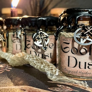 May include: Four small glass jars with black wax lids and gold charms. Each jar contains a brown powder and has a label that reads "Goofer Dust - An Original Hoodoo Formula".