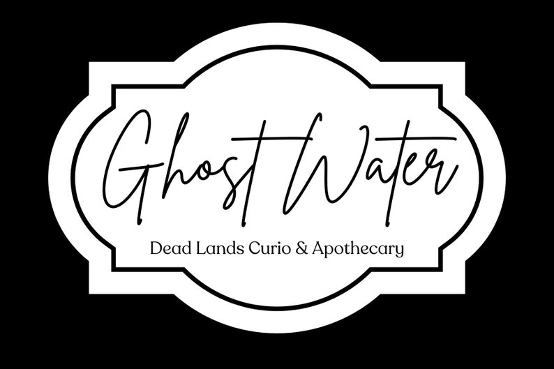 May include: A white rectangular label with rounded, decorative edges and a black border. The text Ghost Water is written in a black cursive script, with the text Dead Lands Curio & Apothecary printed in a smaller, simple black serif font below.