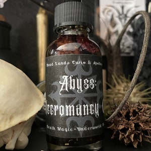 May include: A small glass bottle with a black dropper top and a black label. The label reads "Dead Lands Curio & Apothecary Abyss: Necromancy Oil Death Magic - Underworld"