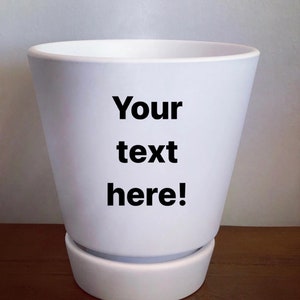 May include: White ceramic planter with a saucer. The planter has the text "Your text here!" printed on the side.