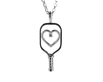 May include: A silver necklace with a pendant shaped like a pickleball paddle with a heart-shaped design with small diamonds.