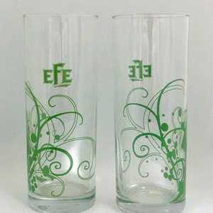 May include: Two clear glass drinking glasses with a green floral design and the word "EFE" printed on the front.