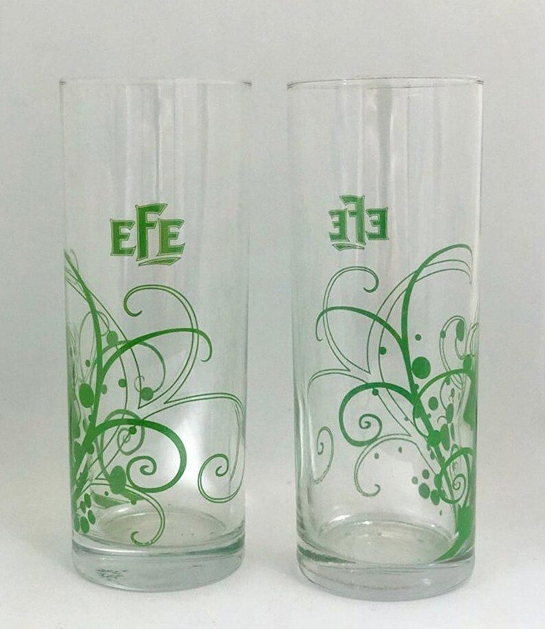 May include: Two clear glass drinking glasses with a green floral design and the word "EFE" printed on the front.