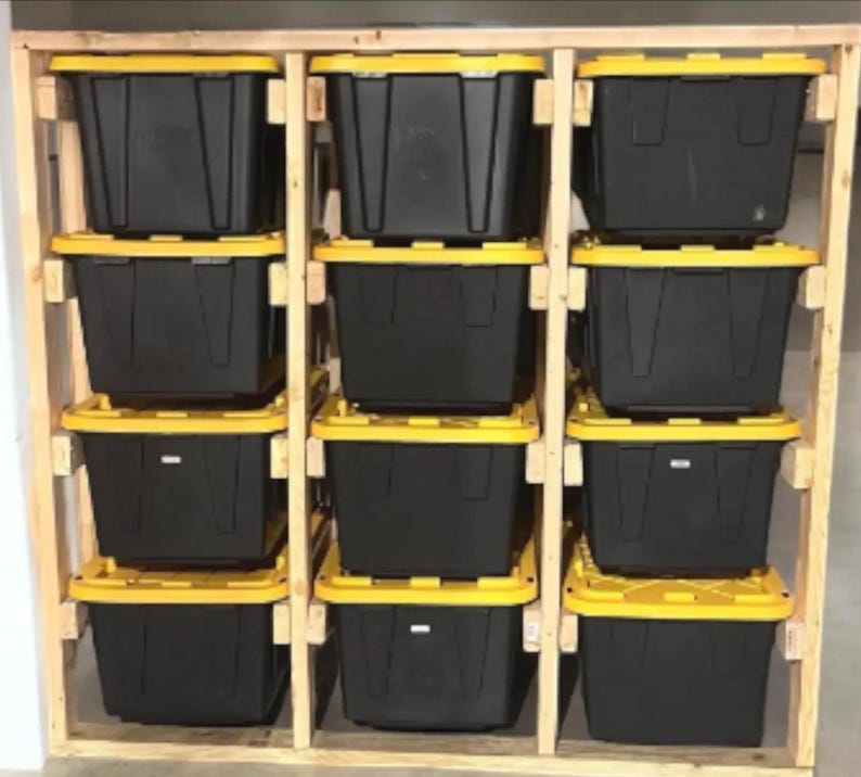 May include: A wooden storage unit with twelve black plastic bins with yellow lids. The bins are arranged in a grid, supported by a natural wood frame. The storage unit is designed for organization.