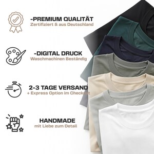 May include: A stack of various colored crew neck t-shirts. Colors include black, dark green, navy, olive green, beige, light gray, and white. Text on the left side reads "PREMIUM QUALIT&Auml;T", "DIGITAL DRUCK", "HANDMADE".
