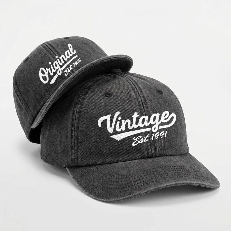 May include: Two dark gray baseball caps. One cap has the word "Original" and "Est. 2025" in white script. The other cap has the word "Vintage" and "Est. 1991" in white script.