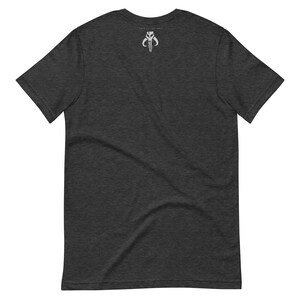 Puede incluir: Una camiseta gris oscuro jaspeada con un s&iacute;mbolo mandaloriano blanco en la espalda.
