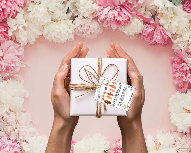May include: A white gift box wrapped in twine with a gift tag that reads "Women like you make the world better." The gift tag has a colorful illustration of hands.