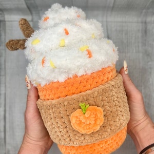 May include: A crocheted pumpkin spice latte plush toy with a white whipped cream top, orange and brown cup, and a small orange pumpkin applique.