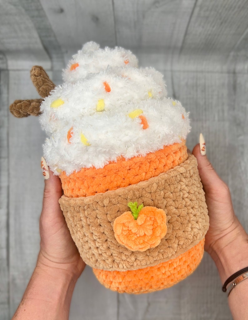 May include: A crocheted pumpkin spice latte plush toy with a white whipped cream top, orange and brown cup, and a small orange pumpkin applique.